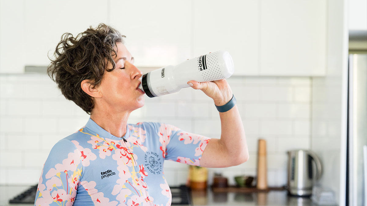 Woman drinking water in cycling gear during summer