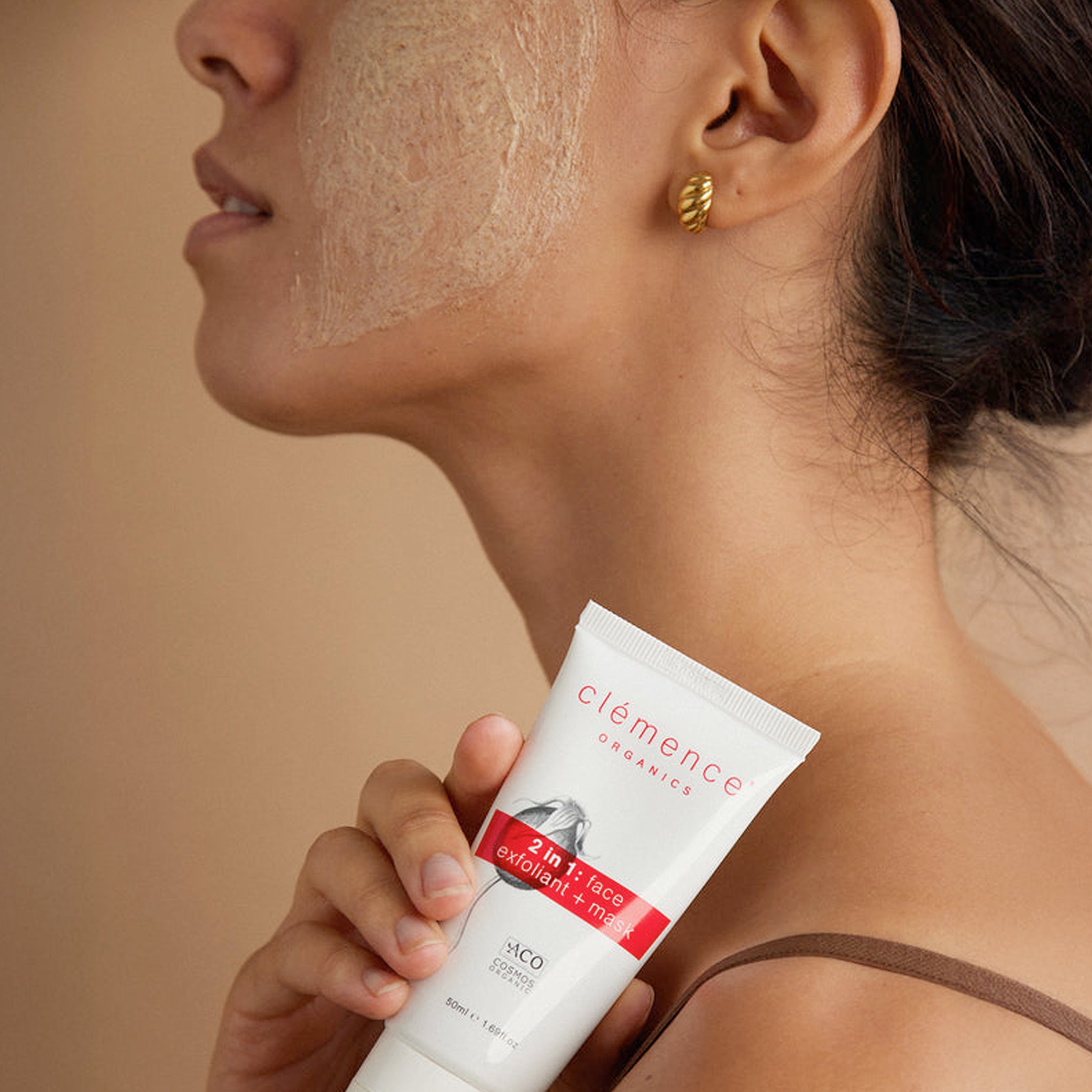 A woman holding a tube of Clémence Organics 2 in 1 Exfoliant & Mask