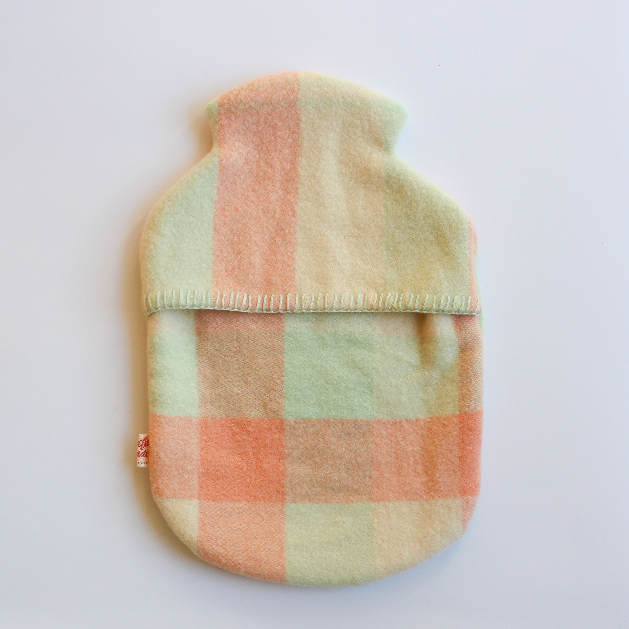 Plaid patterned hot water bottle cover on a white background