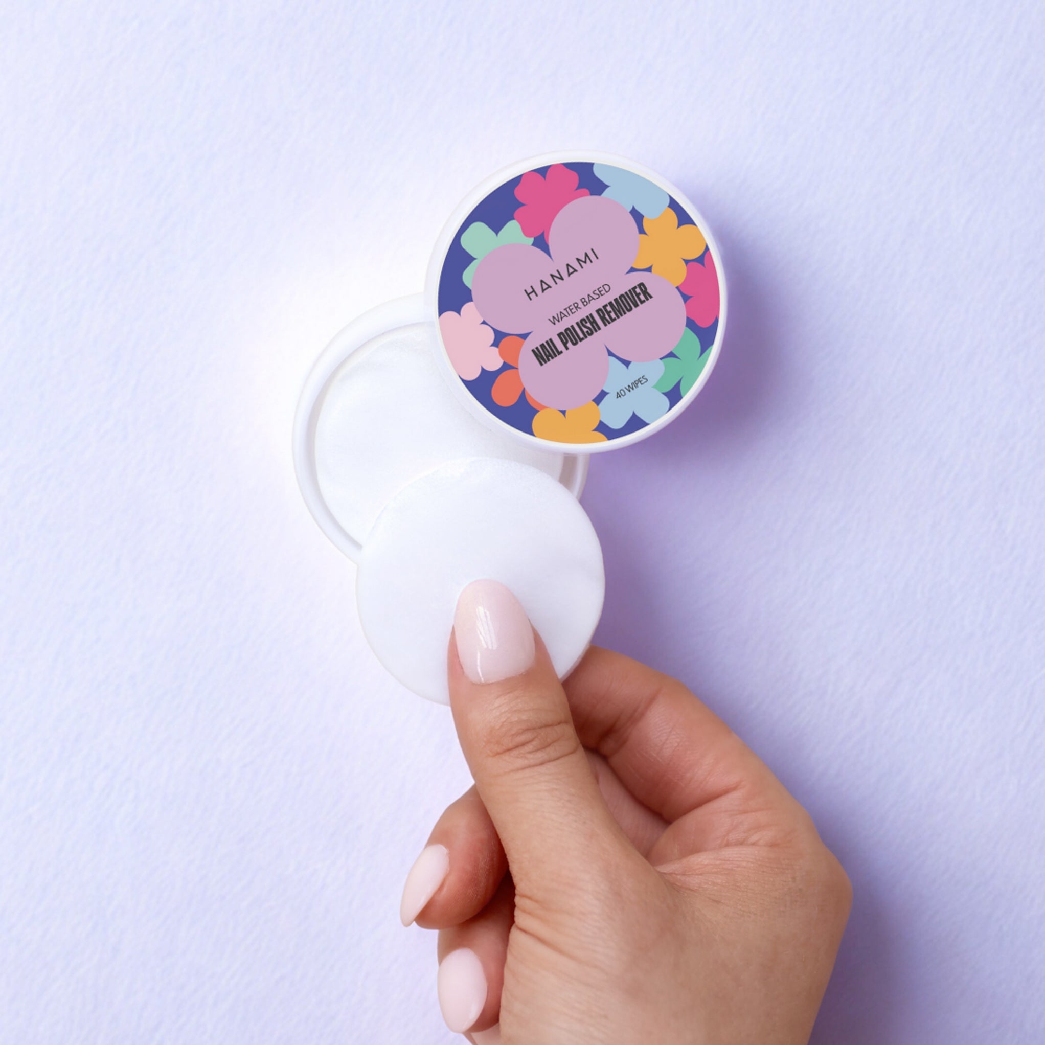 Hand removing an Hanami Water-based Nail Polish Remover Wipe from its pack.
