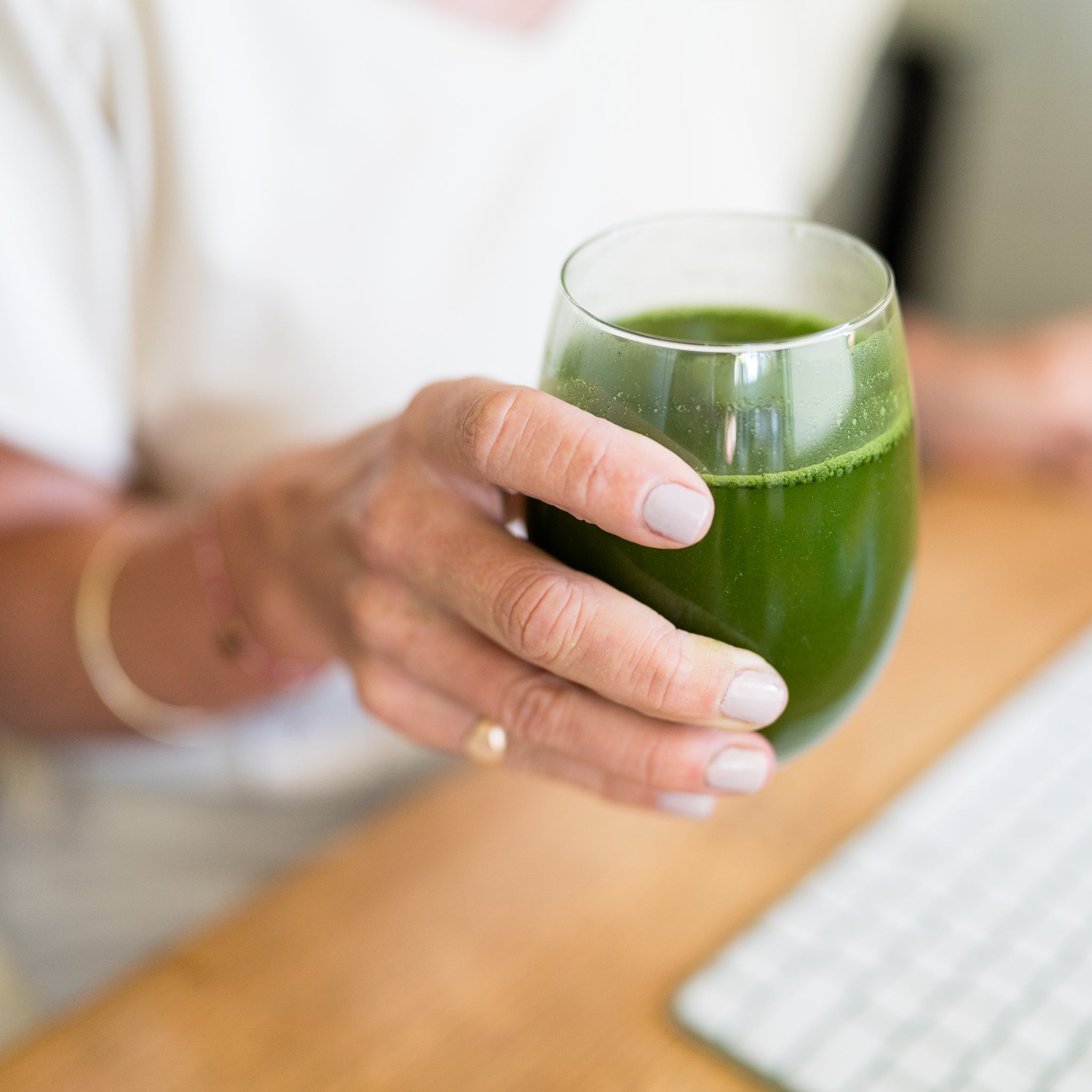 Amy holding a glass of Daily Greens
