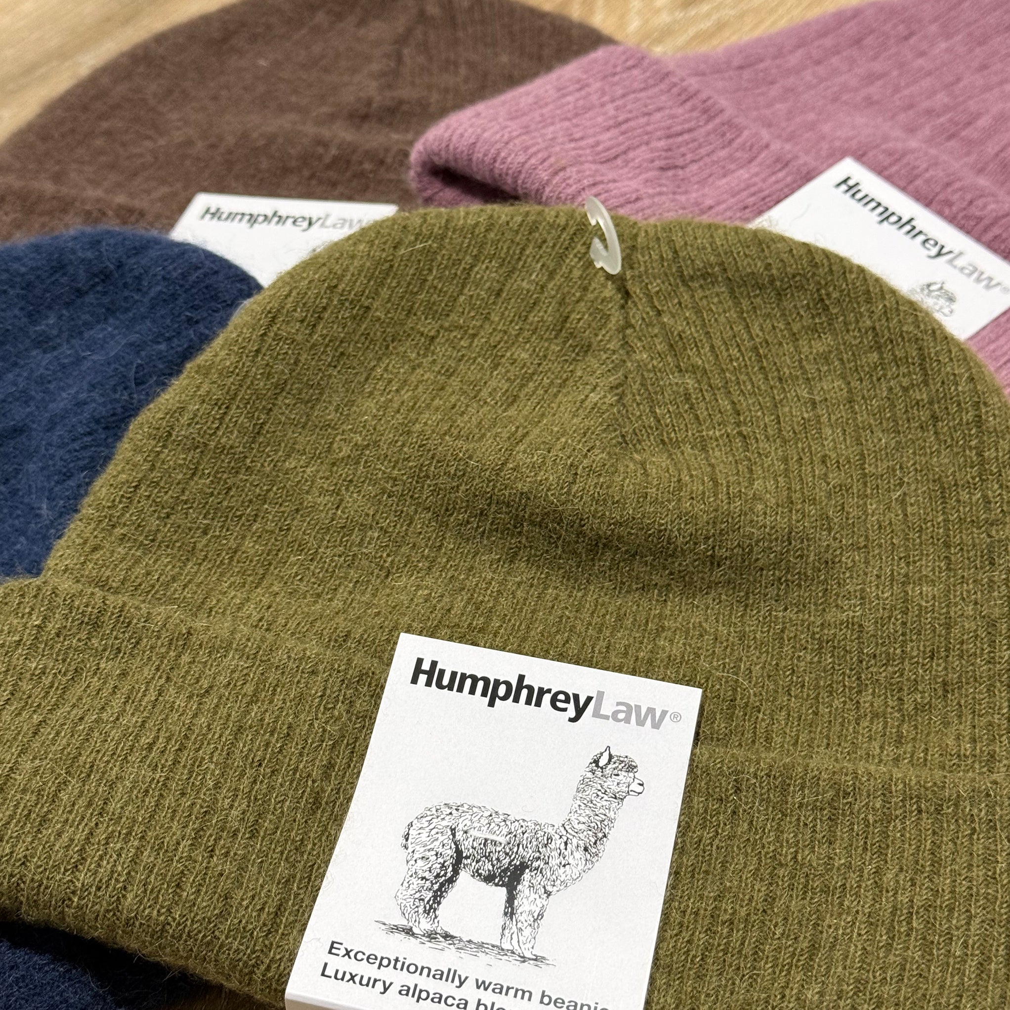 Collection of beanies with 'Humphrey Law' labels on a wooden surface