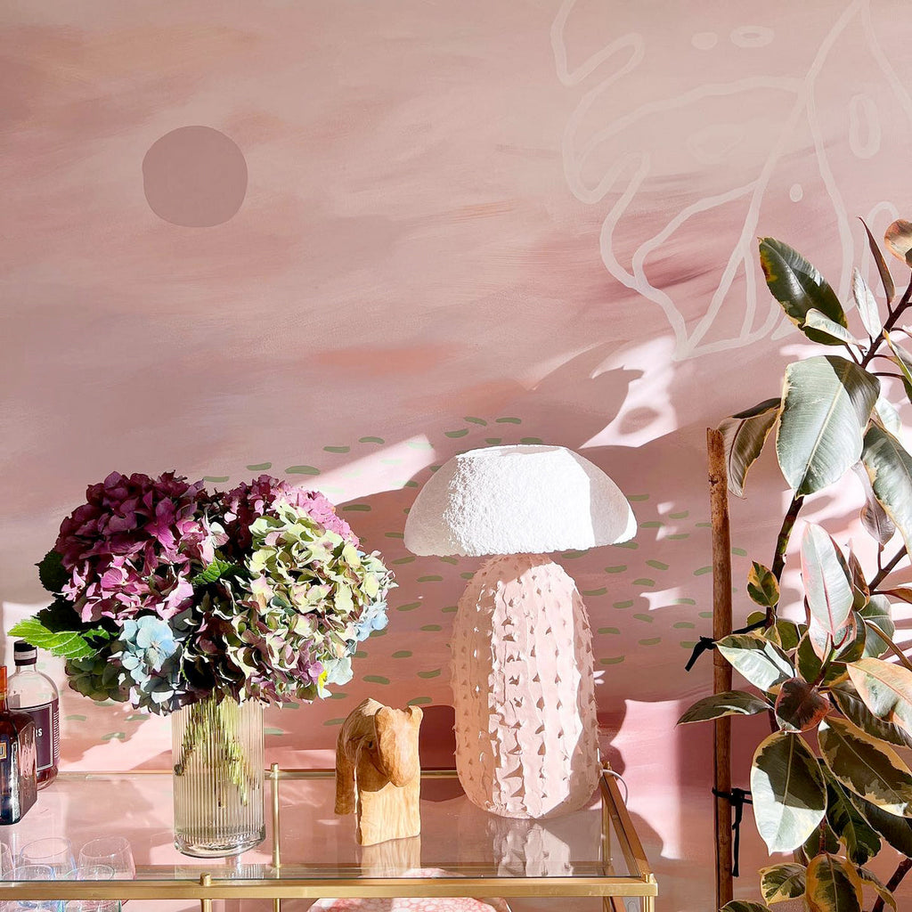 A photo taken at Amy's house of the pink mural and her hand-made, ceramic lamp. 