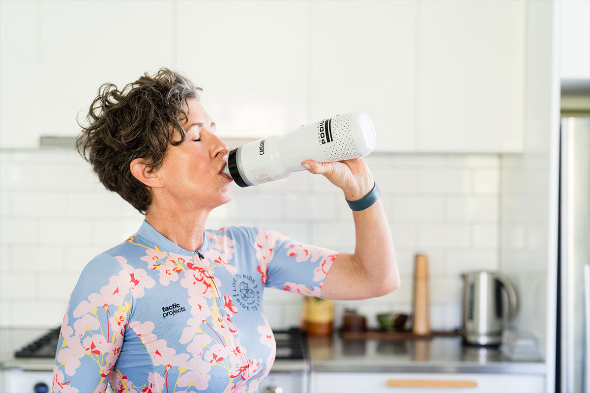 Woman drinking water in cycling gear during summer
