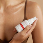 A woman spraying Clémence Organics Ultimate Biome Spritz on her chest