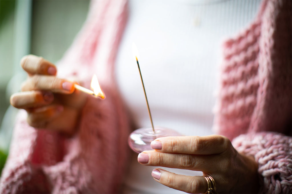 Amy Crawford lighting Australian Sandalwood Incense in a pink glass pebble incense holder. 