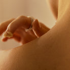 Close-up of a hand applying a skincare product to a person's shoulder.