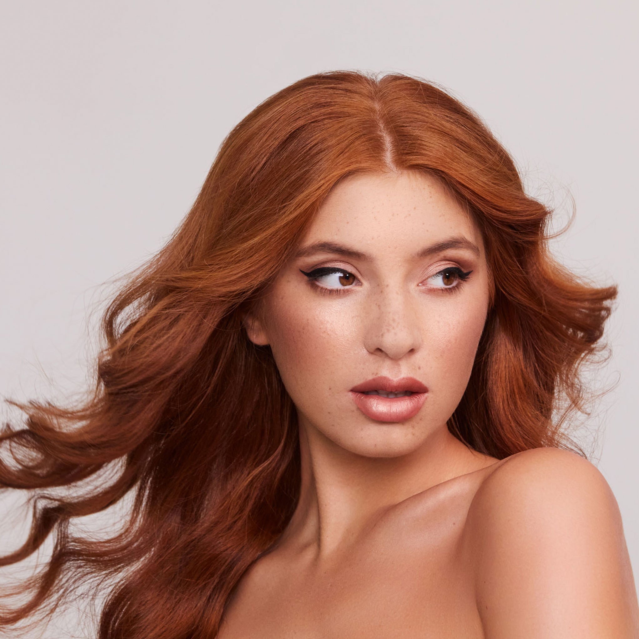 Woman with long, wavy red hair against a light background
