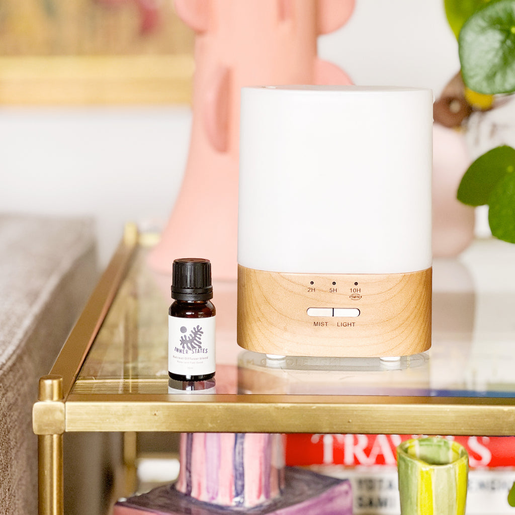 A 10ml bottle of Inner States Retreat Diffuser Blend sitting next to a diffuser. 