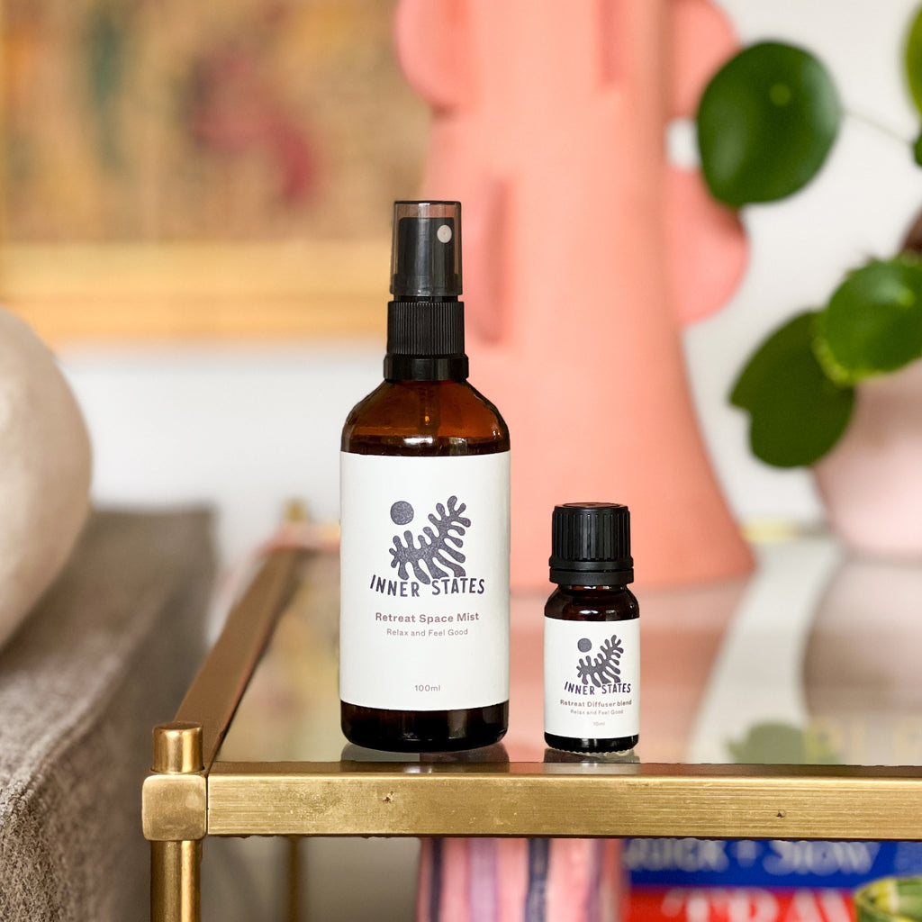 A 10ml bottle of Inner States Retreat Diffuser Blend sitting next to a bottle of Inner States Retreat Space Mist.
