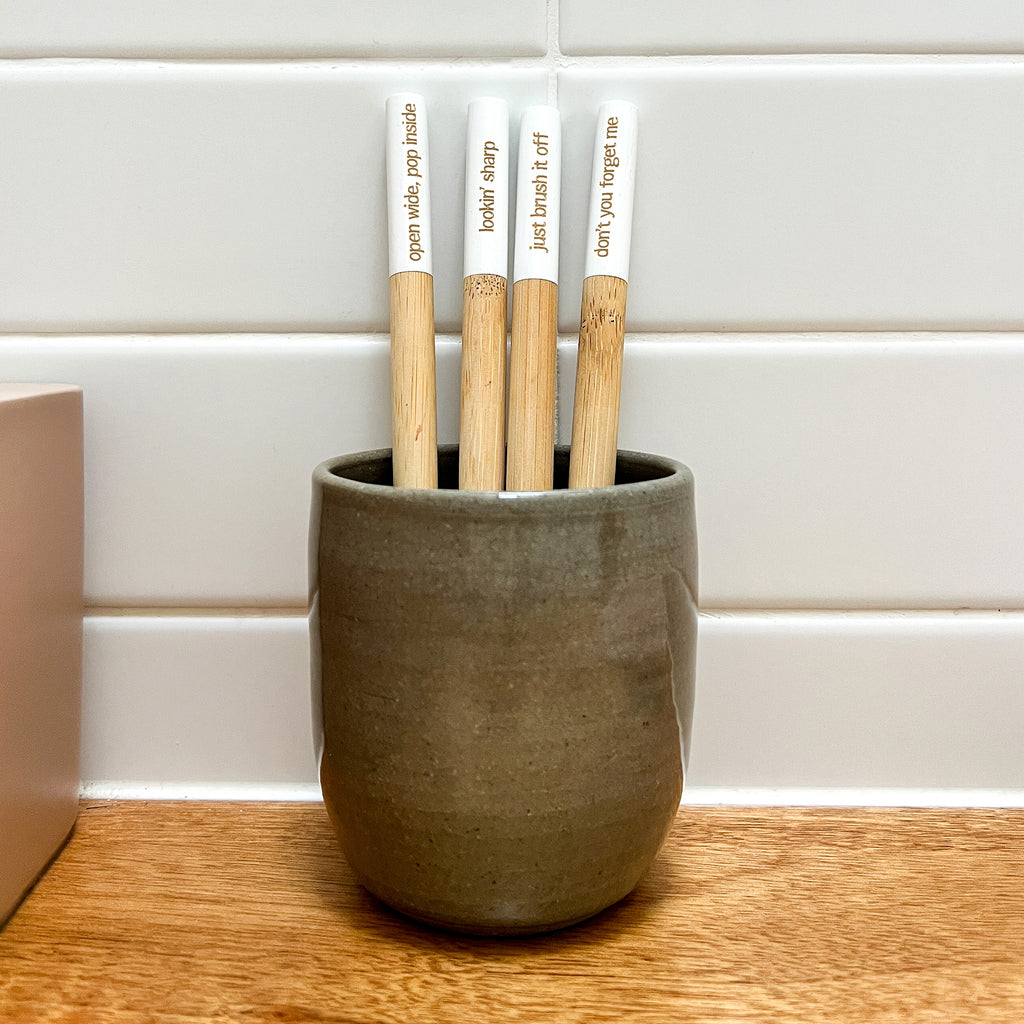 The Holistic Ingredient bamboo toothbrushes in a ceramic cup in Amy's bathroom