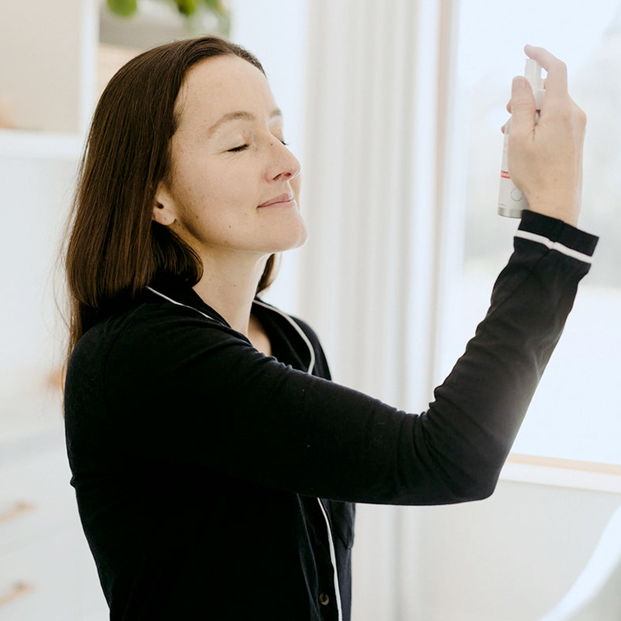 Woman applying Clémence Organics Tone & Hydrate Spritz to her face