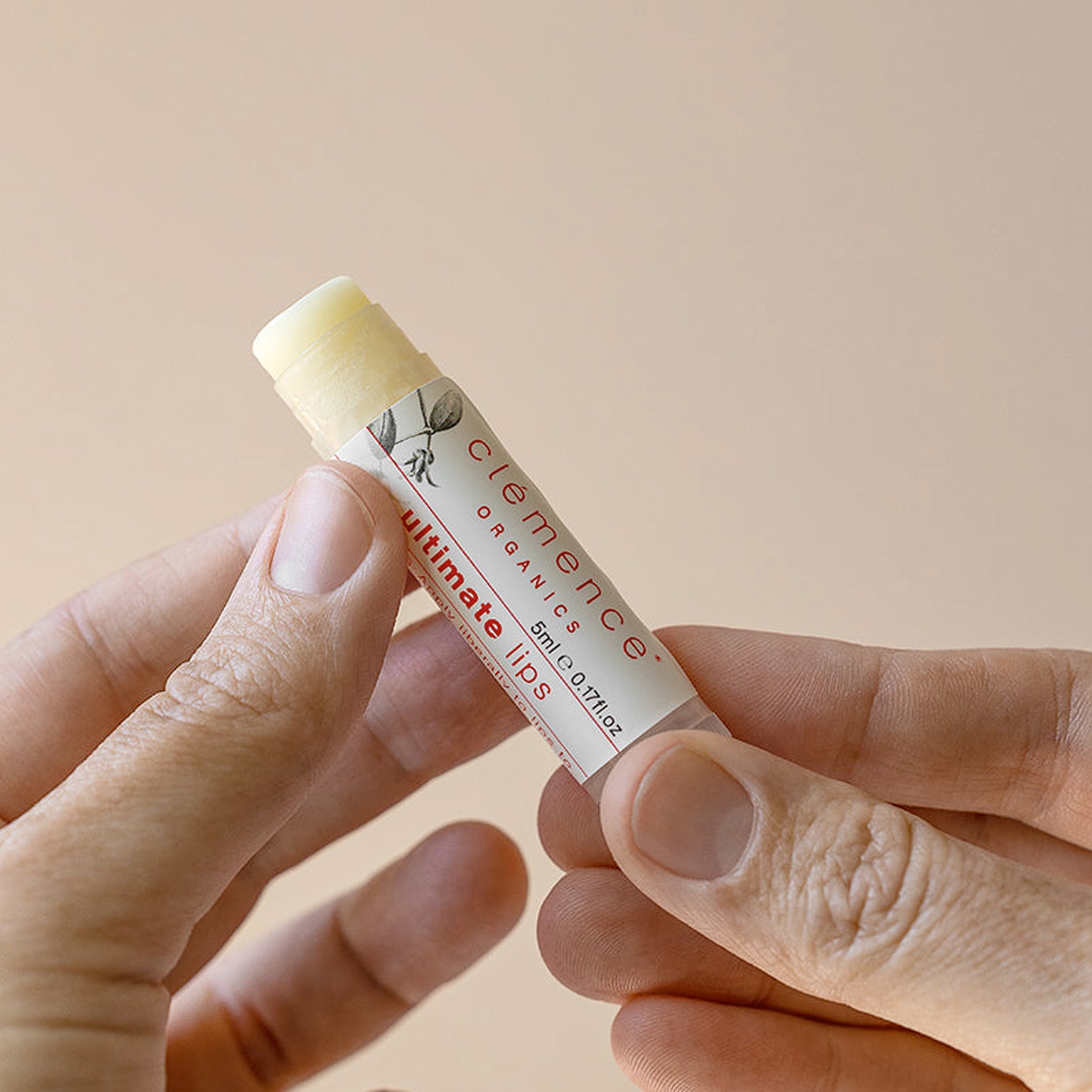 A person holding an open stick of Clémence Organics Ultimate Lips
