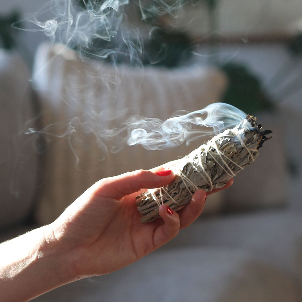 Amy burning a Sage Smudge Stick by The Holistic Ingredient